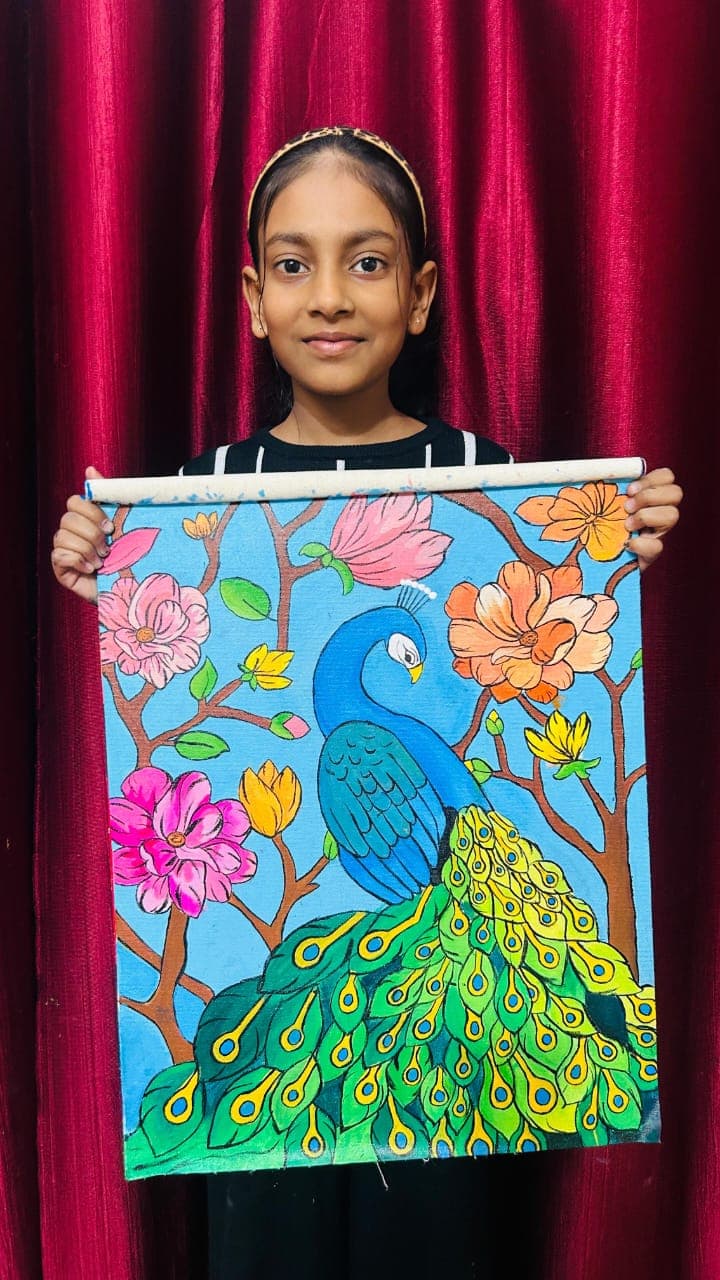 Khushi holding her vibrant peacock painting with colorful flowers on a blue background
